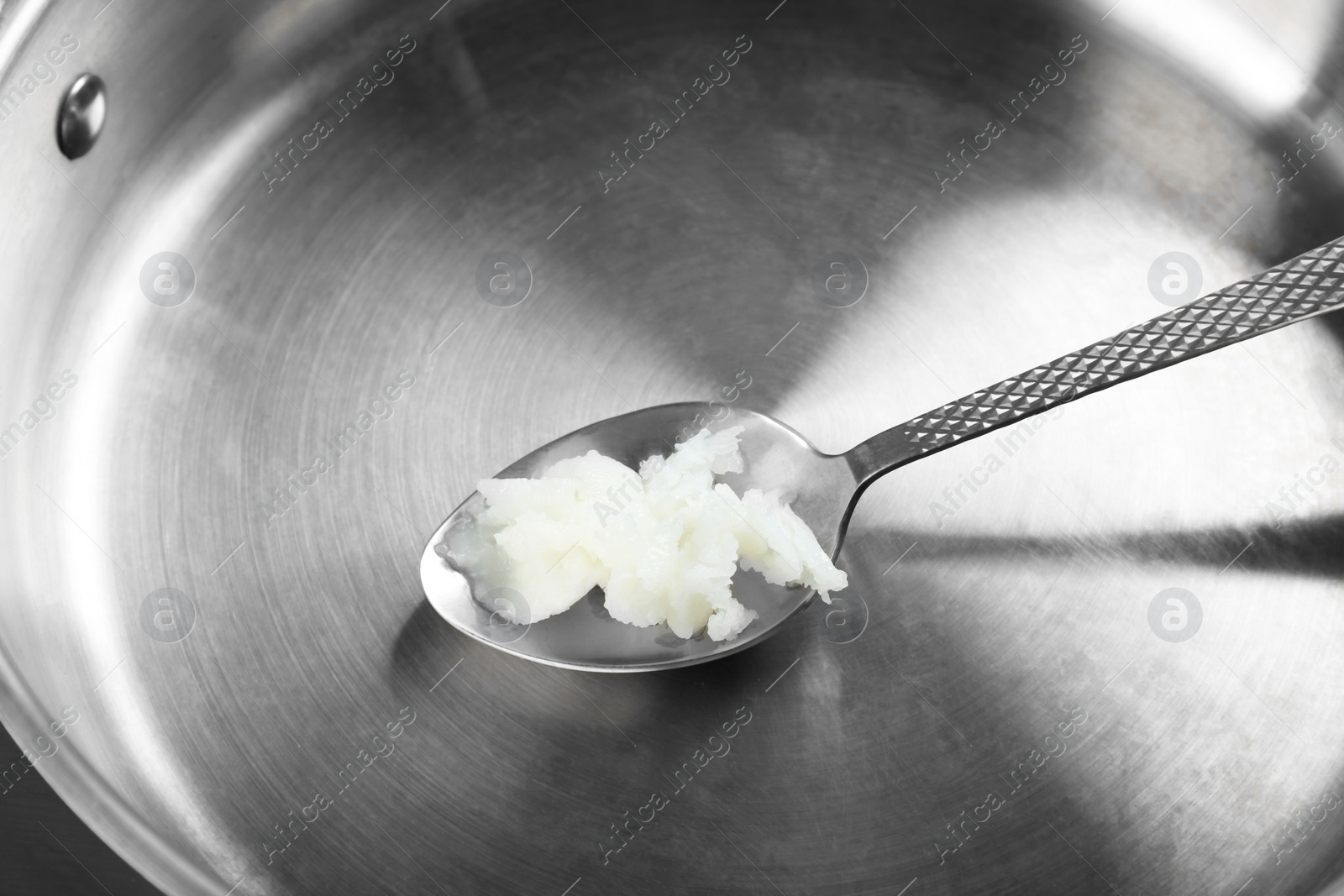 Photo of Frying pan with organic coconut cooking oil and spoon, closeup