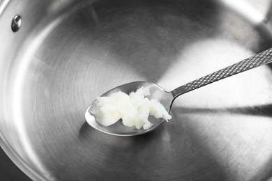 Frying pan with organic coconut cooking oil and spoon, closeup