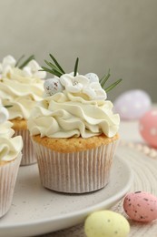 Tasty Easter cupcakes with vanilla cream and candies on table