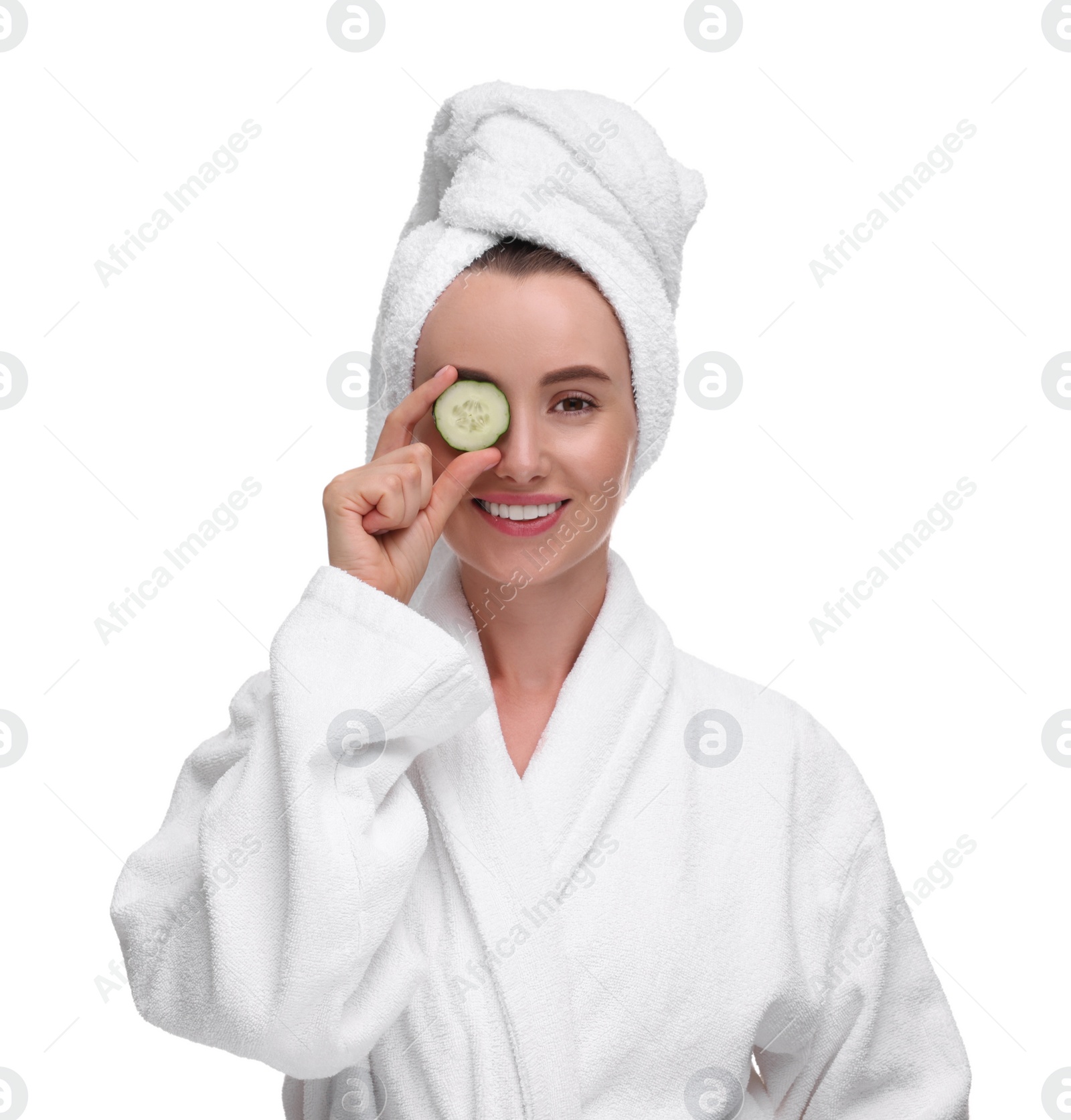 Photo of Beautiful woman in bathrobe covering eye with piece of cucumber on white background