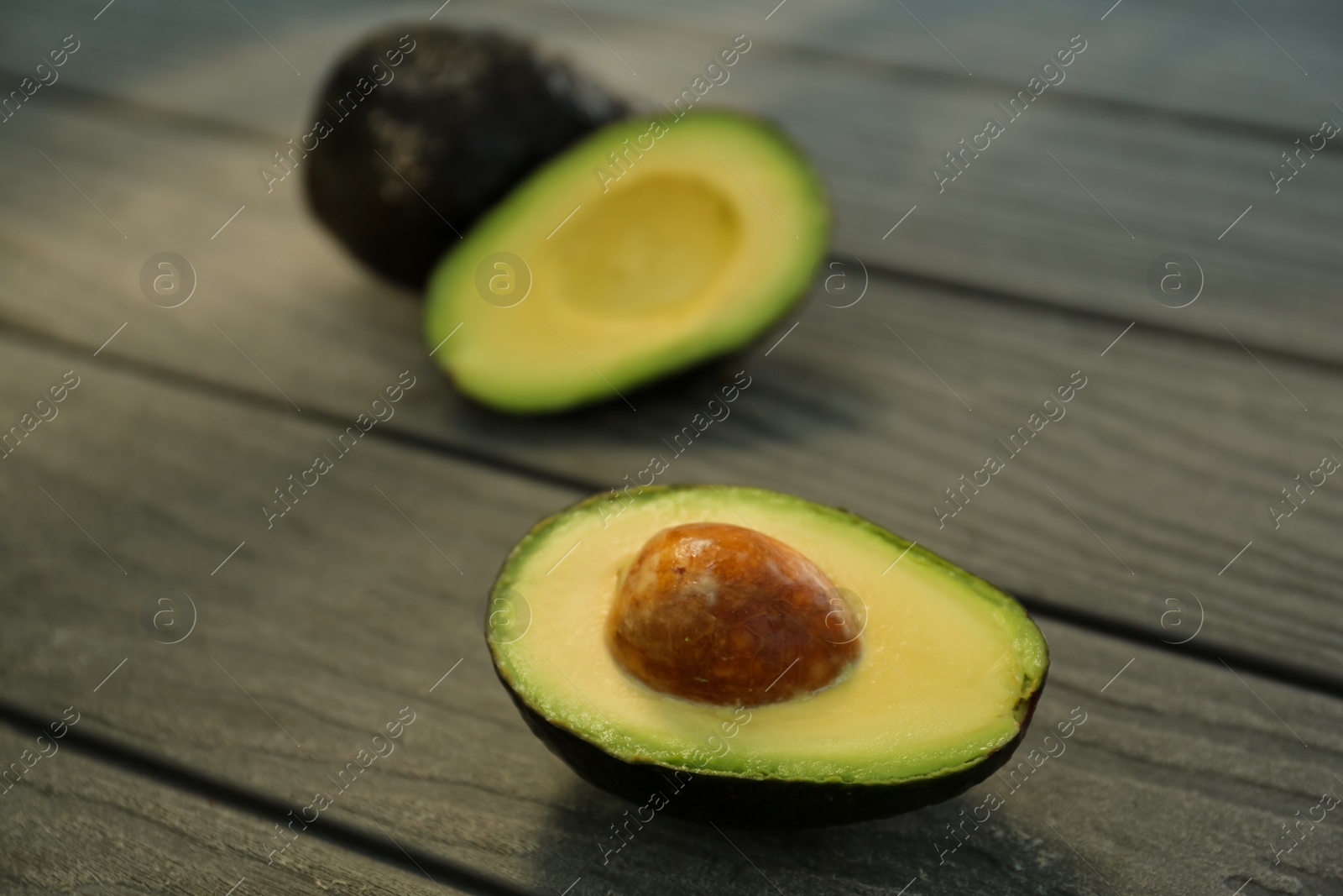 Photo of Half and whole fresh avocados on wooden table, closeup