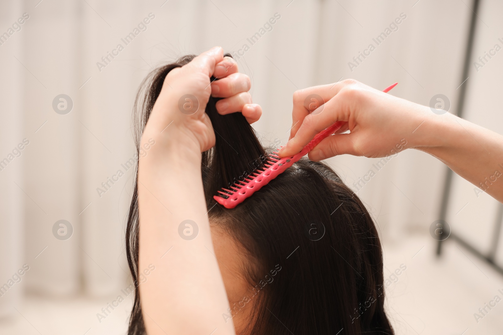 Photo of Hair styling. Professional hairdresser combing woman's hair indoors, closeup