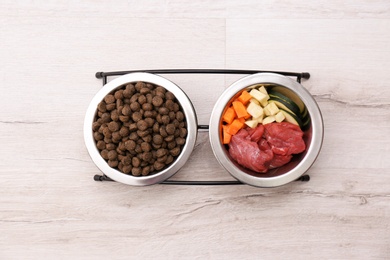 Photo of Bowls with dry and natural dog food on light background, top view