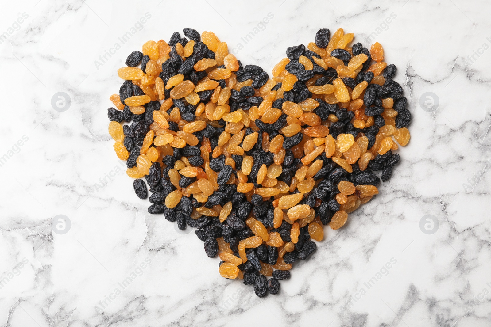 Photo of Heart shape of raisins on marble background. Dried fruit as healthy snack