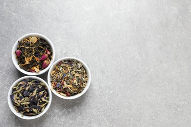 Flat lay composition with different dry teas on light grey table, space for text