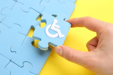 Inclusion concept. Woman putting light blue puzzle with international symbol of access together, closeup