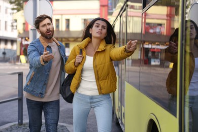 Photo of Being late. Worried couple running towards bus outdoors, space for text
