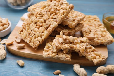 Photo of Delicious peanut bars (kozinaki) and ingredients on light blue wooden table, closeup