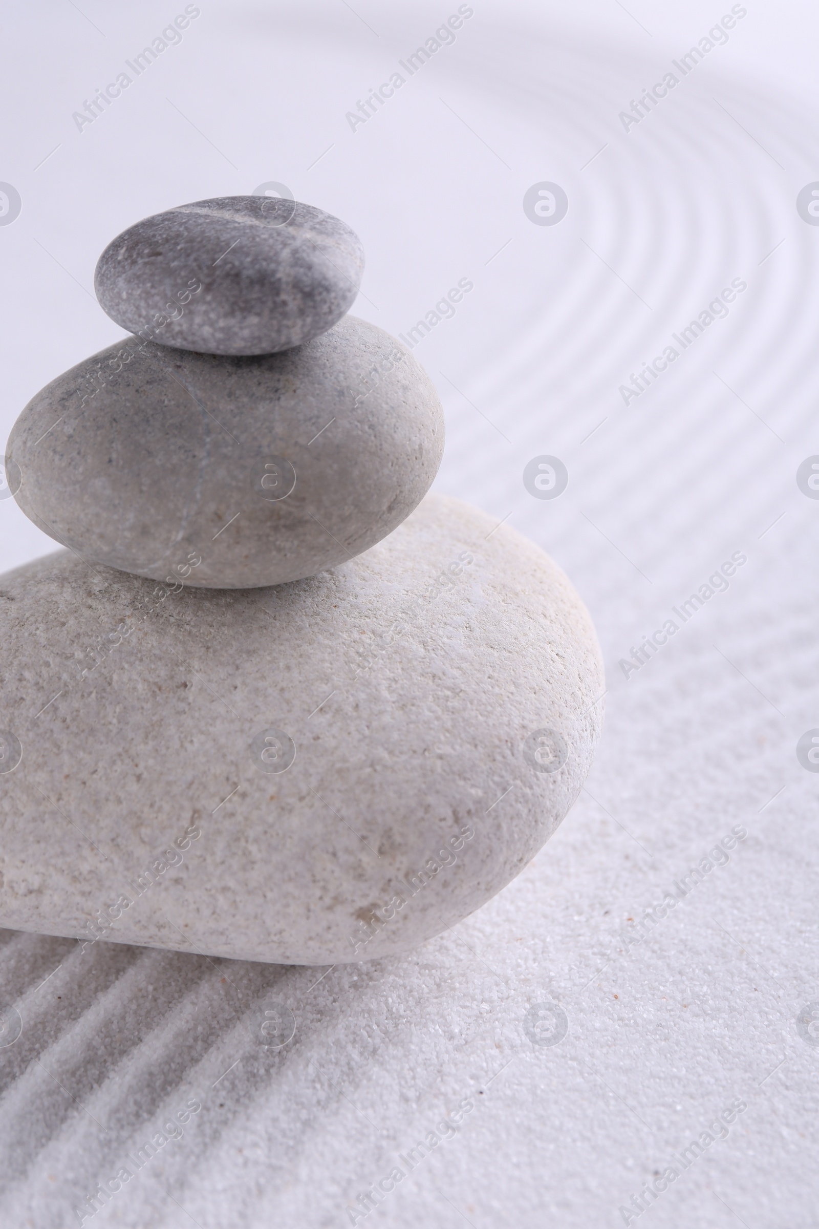 Photo of Zen garden stones on white sand with pattern, closeup