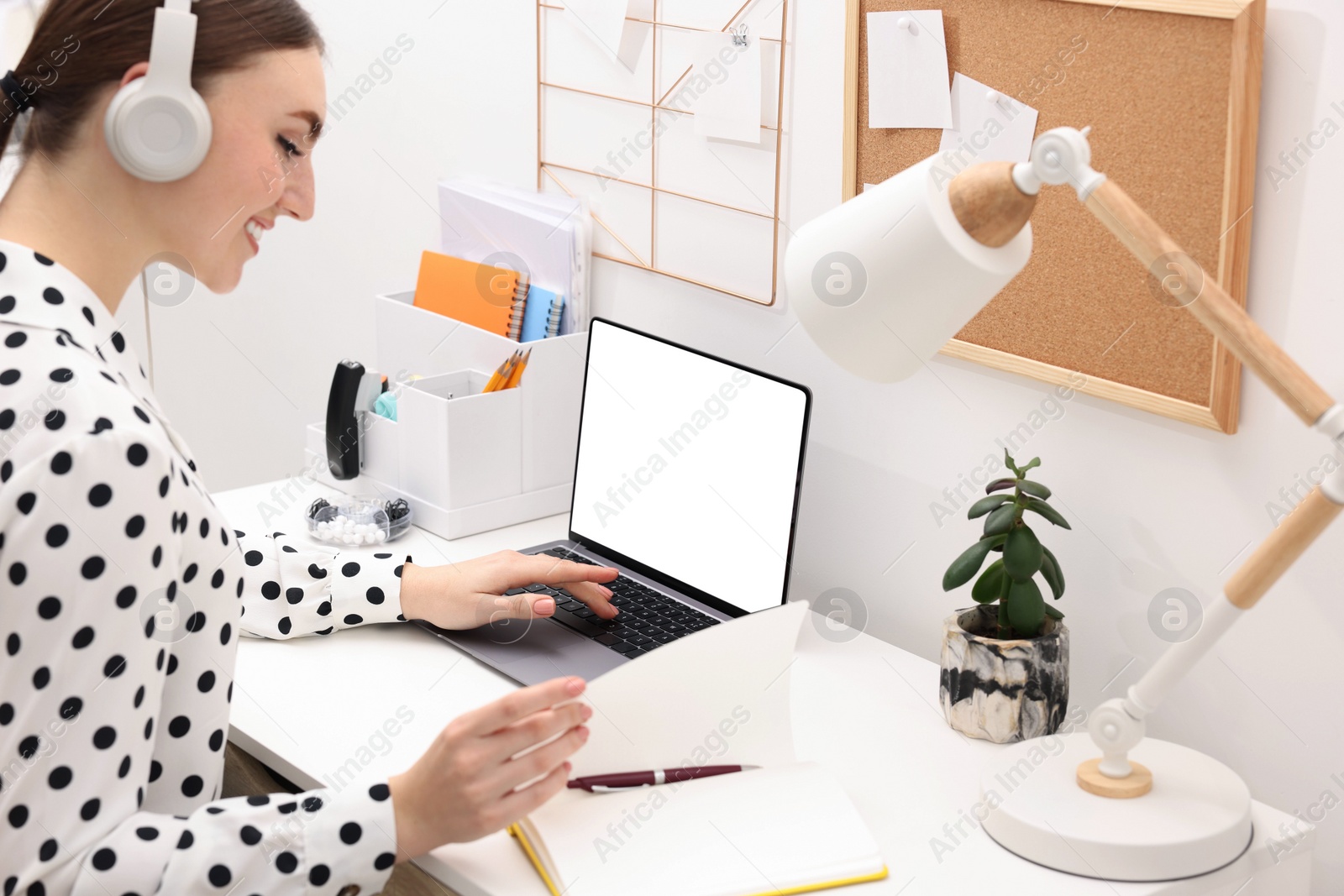 Photo of E-learning. Young woman using laptop during online lesson at table indoors