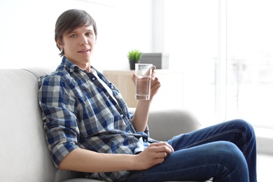 Photo of Portrait of young man drinking water on sofa