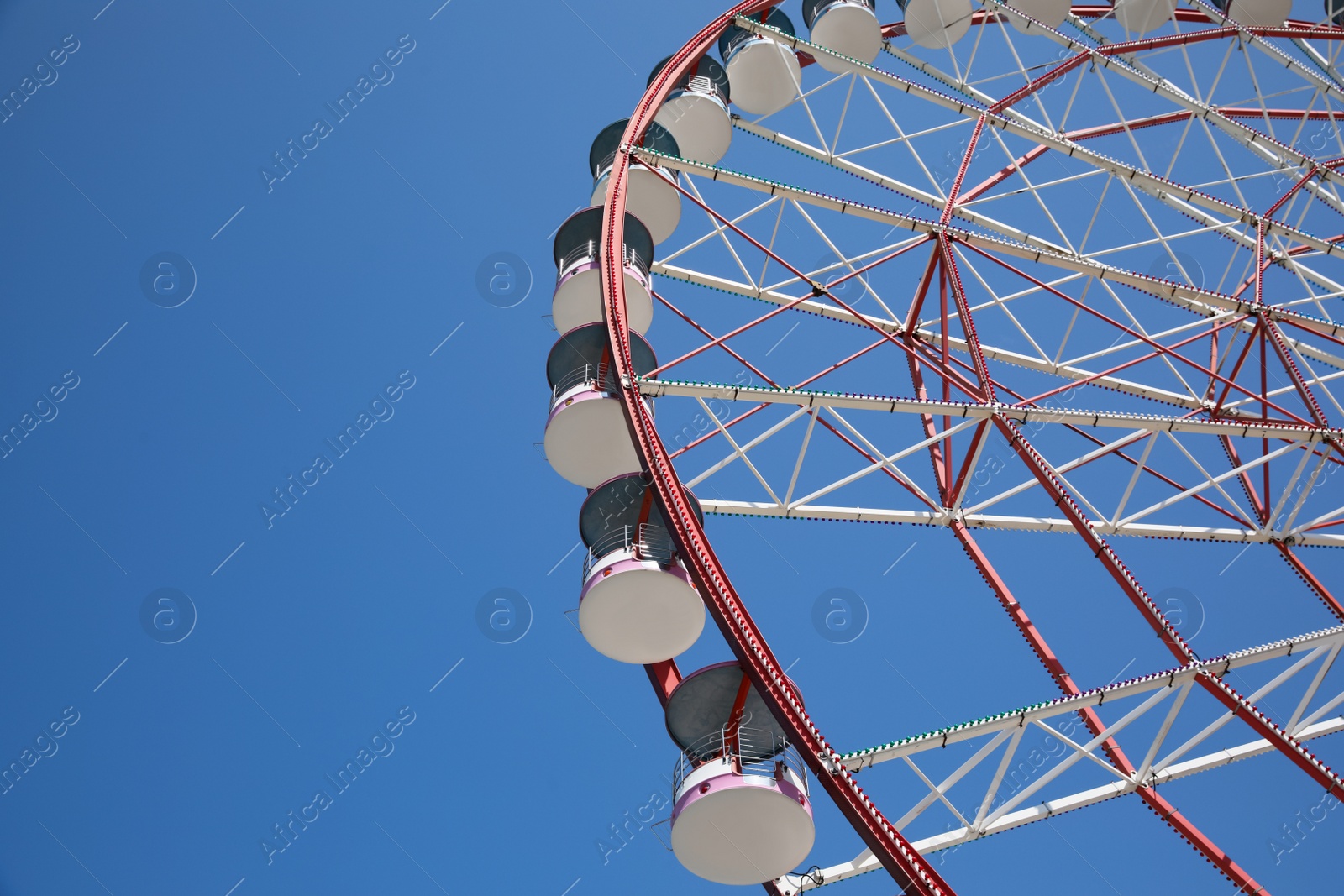 Photo of Beautiful large Ferris wheel against blue sky, low angle view