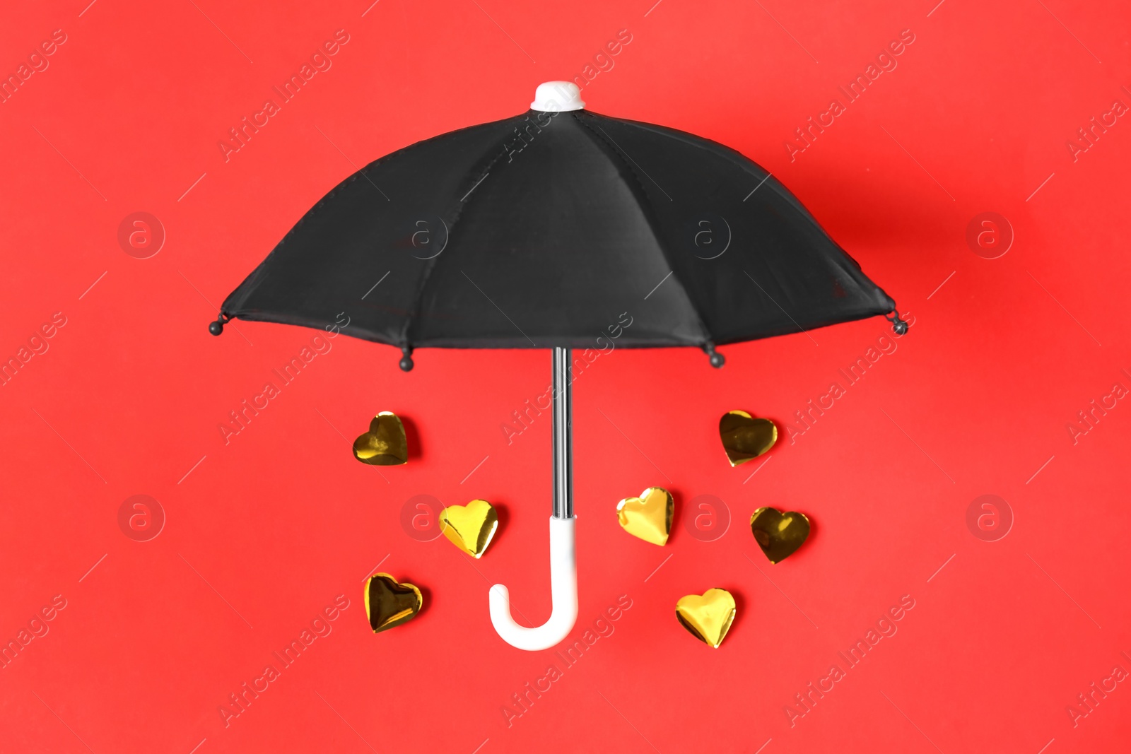 Photo of Umbrella and golden hearts on red background, flat lay