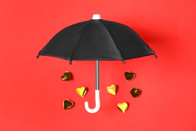 Umbrella and golden hearts on red background, flat lay