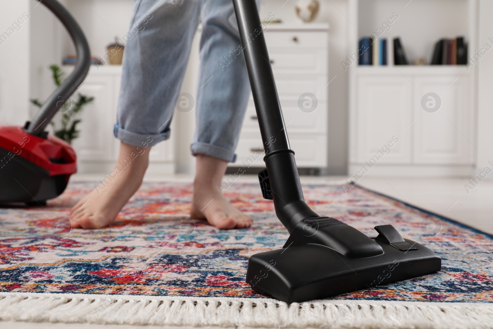 Photo of Woman cleaning carpet with vacuum cleaner at home, closeup. Space for text