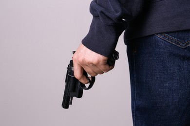 Photo of Man holding gun on grey background, closeup