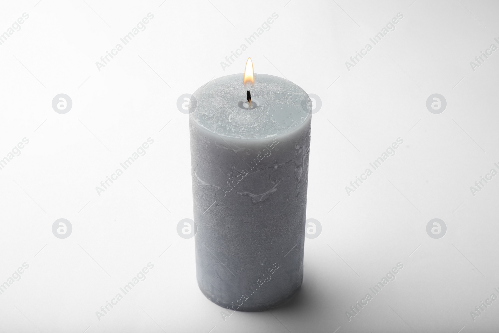 Photo of Burning grey wax candle isolated on white