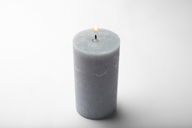 Burning grey wax candle isolated on white