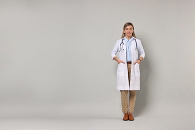 Photo of Portrait of happy doctor with stethoscope on light grey background, space for text