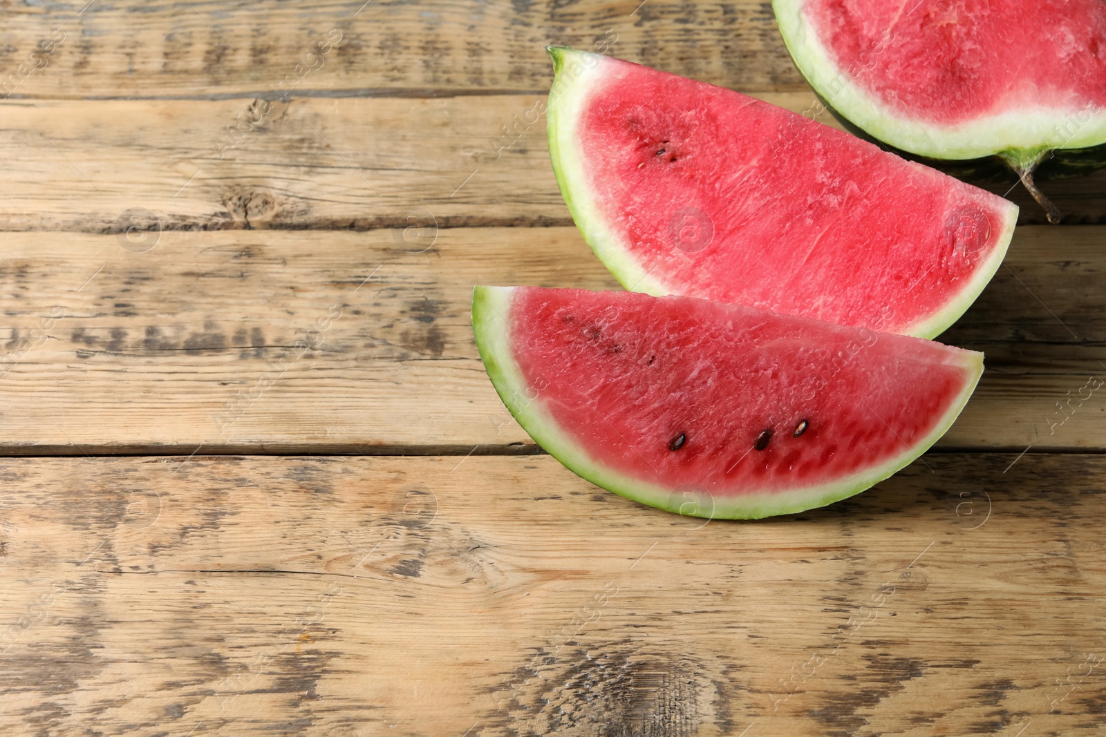 Photo of Delicious fresh watermelon slices on wooden table. Space for text