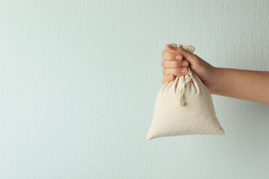 Photo of Woman holding full cotton eco bag on light background, closeup. Space for text