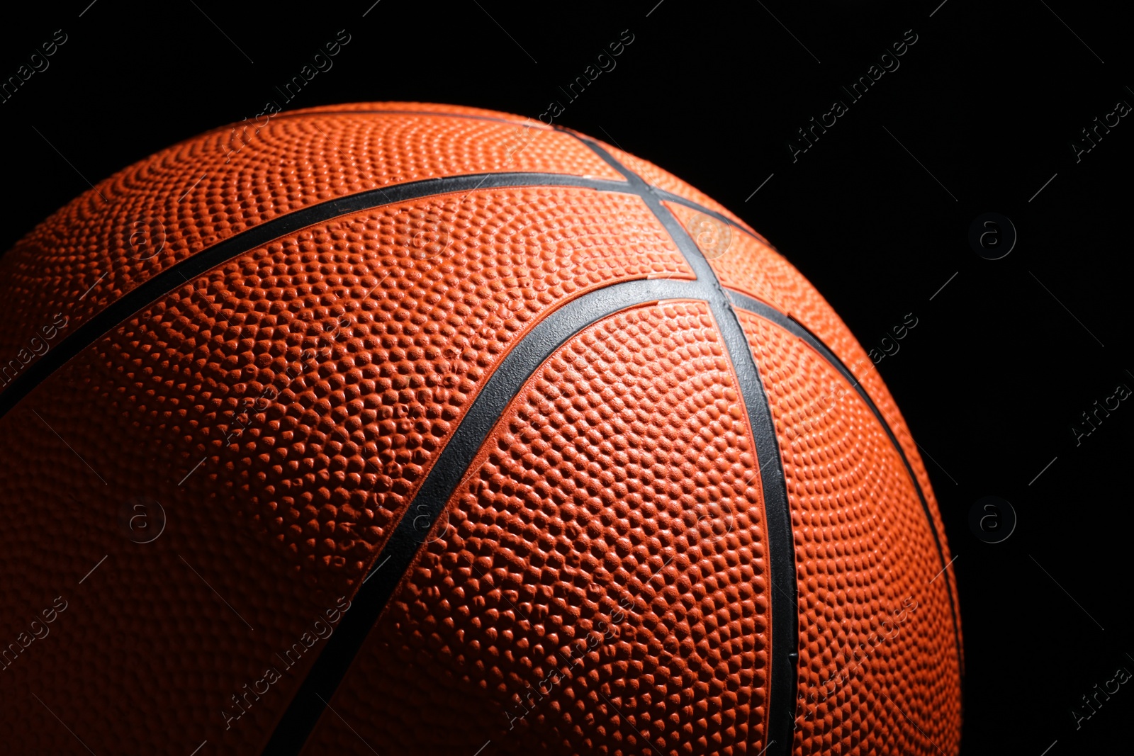 Photo of Orange basketball ball on black background, closeup