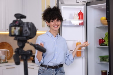 Smiling food blogger explaining something while recording video in kitchen