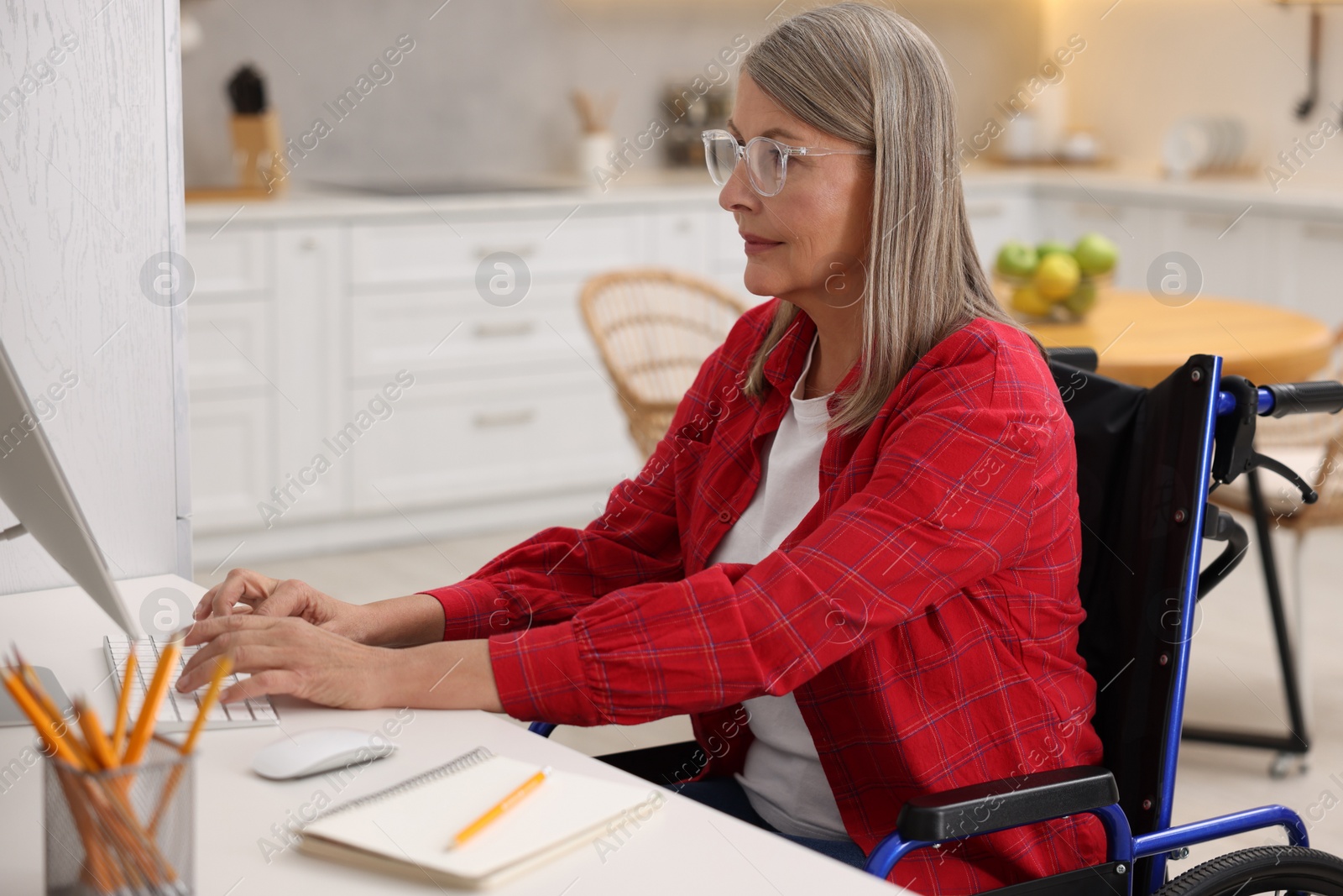 Photo of Woman in wheelchair using computer at table in home office