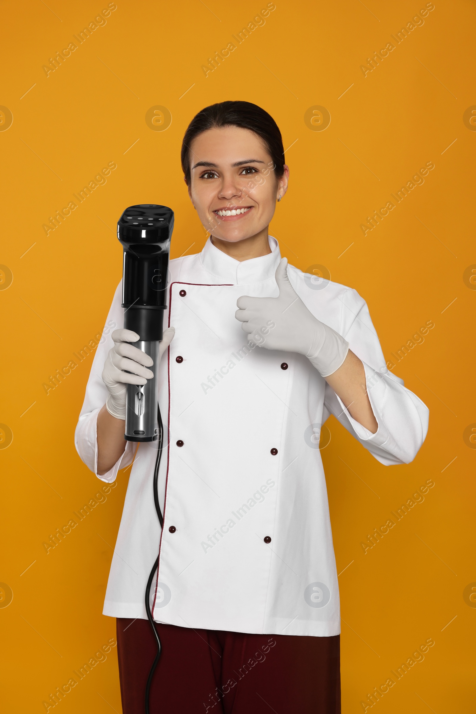 Photo of Chef holding sous vide cooker on orange background