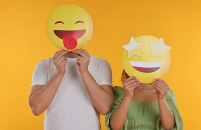 People covering faces with emoticons on yellow background