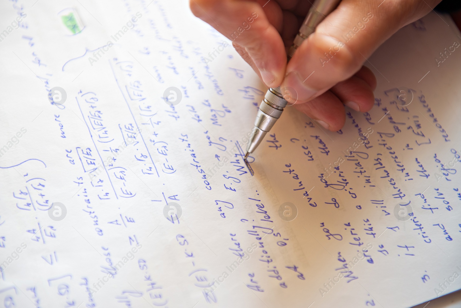 Photo of Student writing mathematical calculations on paper, closeup