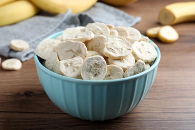 Photo of Freeze dried and fresh bananas on wooden table, closeup