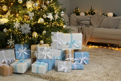 Many gift boxes under decorated Christmas tree in room