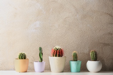 Different potted cacti on table near color background, space for text. Interior decor