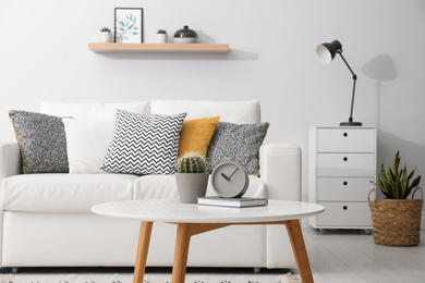 Photo of Clock and cactus on white table in stylish living room