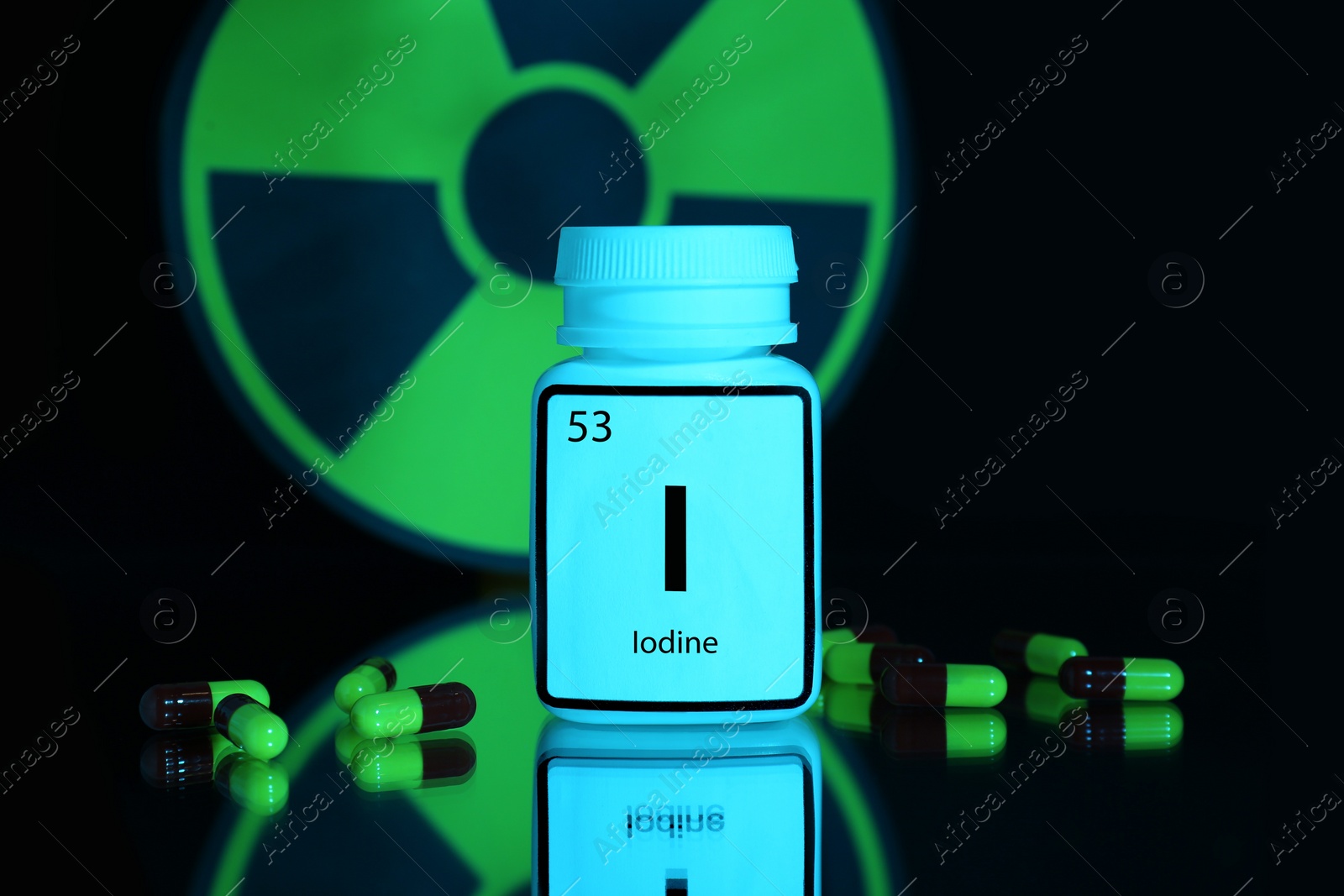 Photo of Bottle of medical iodine, pills and radiation sign on black background, color tone effect