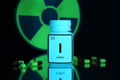 Photo of Bottlemedical iodine, pills and radiation sign on black background, color tone effect