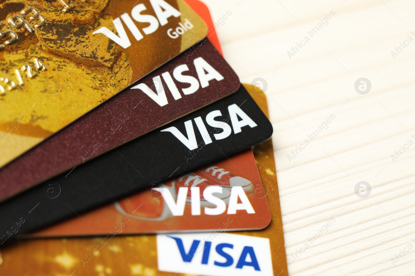 Photo of MYKOLAIV, UKRAINE - FEBRUARY 23, 2022: Bank cards of Visa payment system on wooden table, closeup