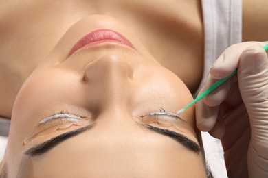 Photo of Young woman undergoing eyelash lamination, closeup. Professional service