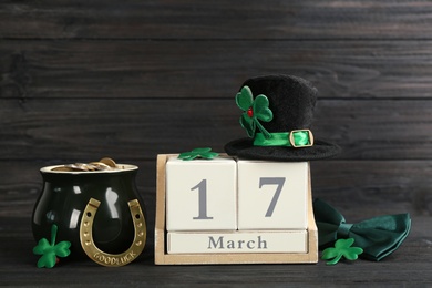 Leprechaun's hat, block calendar and St. Patrick's day decor on black wooden table