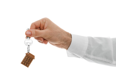 Photo of Real estate agent holding house key with trinket on white background, closeup