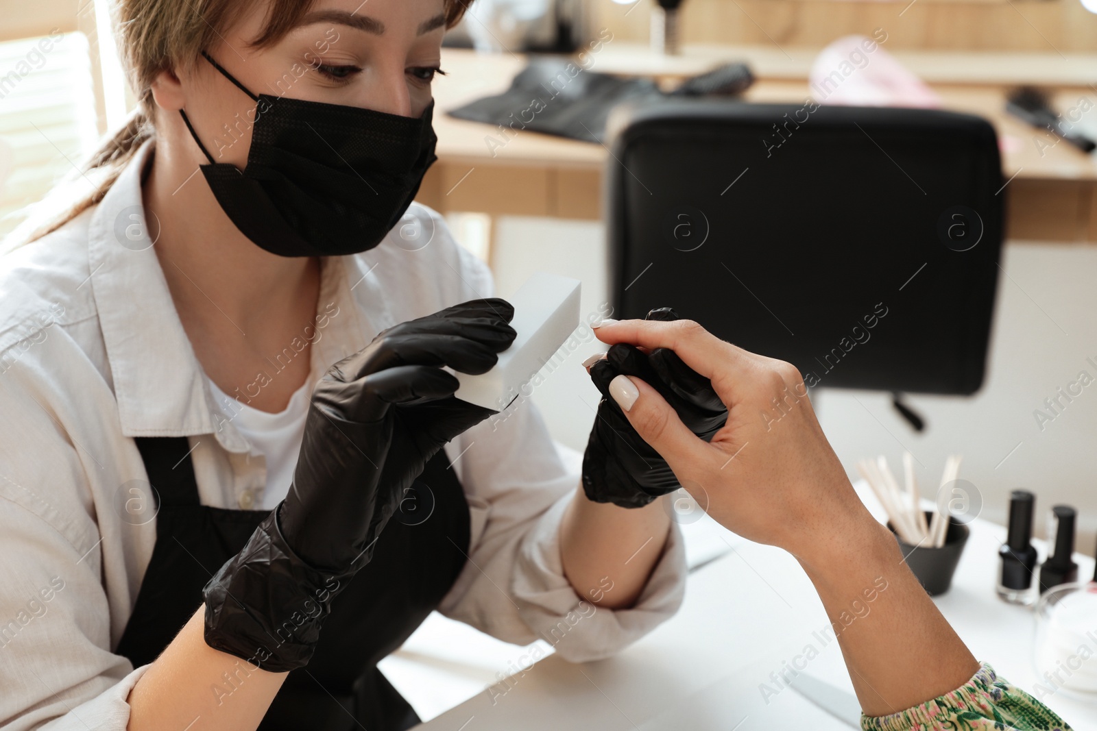 Photo of Professional manicurist working with client in salon, closeup. Beauty services during Coronavirus quarantine