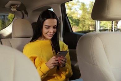 Photo of Beautiful young woman using smartphone in modern car