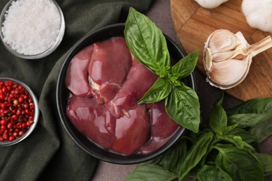 Photo of Bowl of raw chicken liver with basil and products on grey table, flat lay