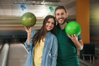 Photo of Happy young couple with balls in bowling club