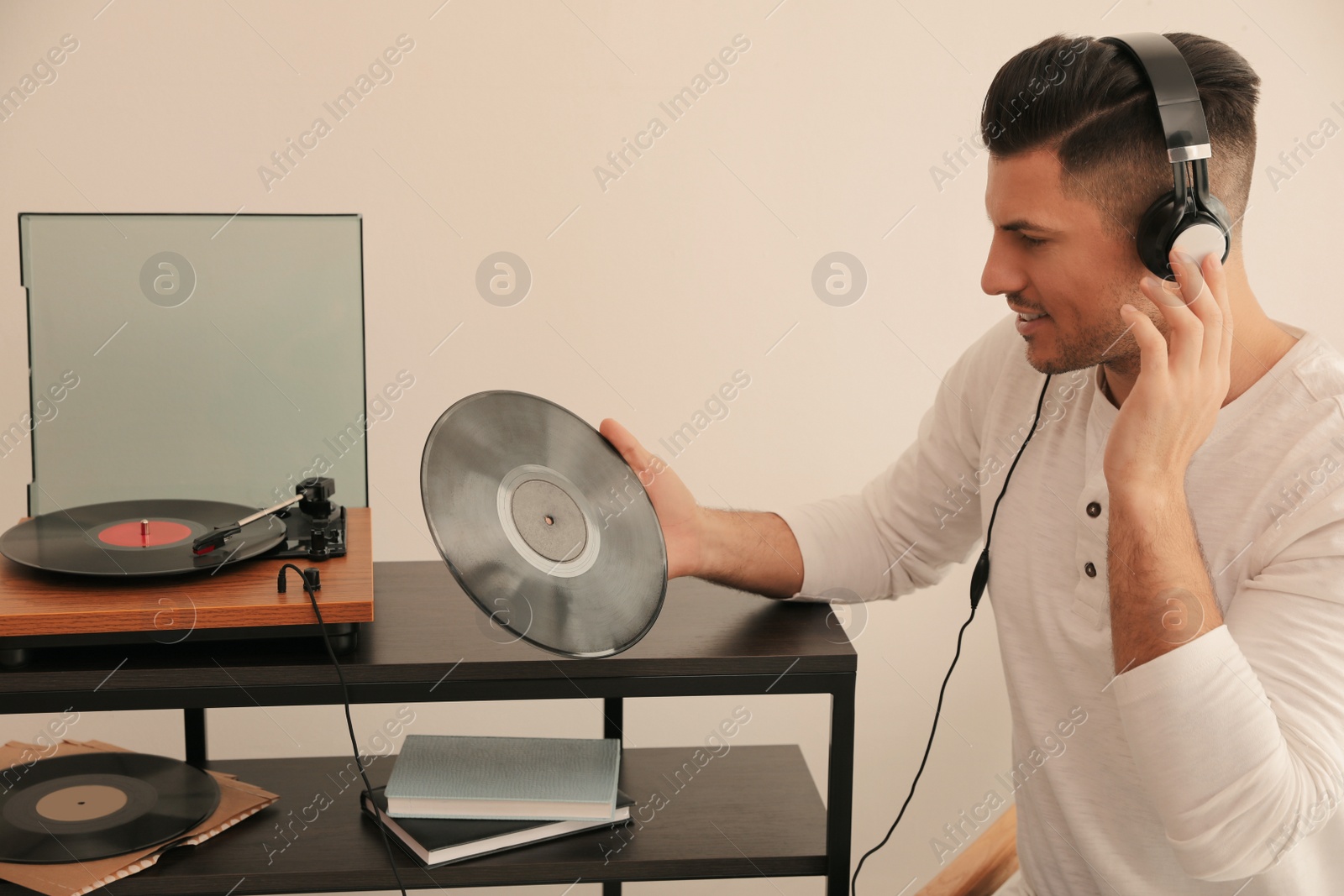 Photo of Happy man listening to music with turntable at home