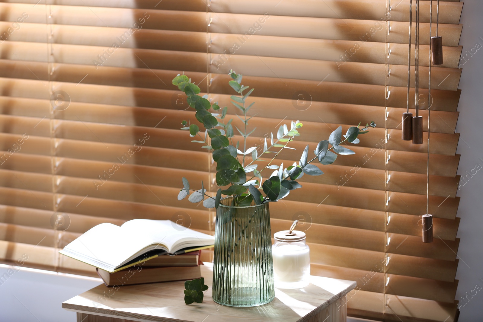 Photo of Vase with fresh eucalyptus branches on table near window in room. Interior design