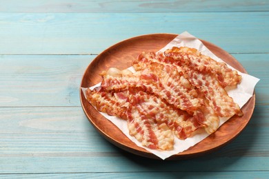 Photo of Delicious fried bacon slices on blue wooden table. Space for text