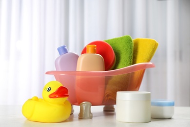 Baby bathing accessories, cosmetic products and toy on table indoors