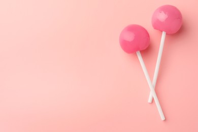 Photo of Tasty lollipops on pink background, flat lay. Space for text